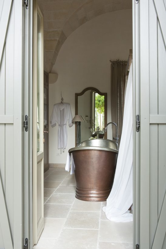 Masseria — the copper bath framed through the shutters, olive tree beyond