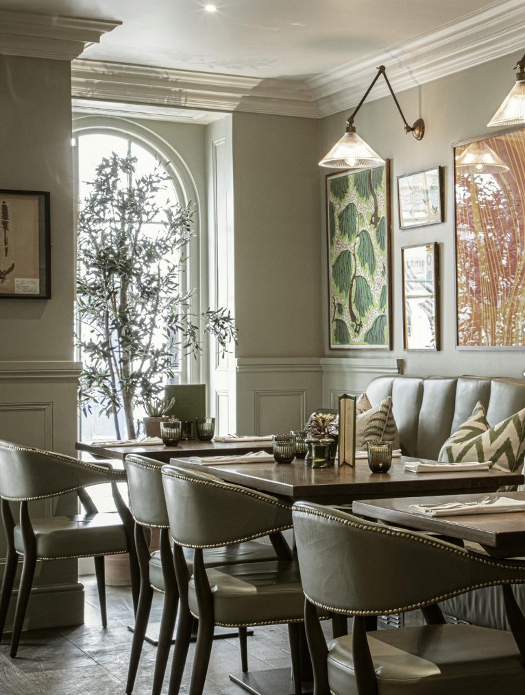 No. 23 dining room — green panelling, studded leather chairs, arched window with olive tree